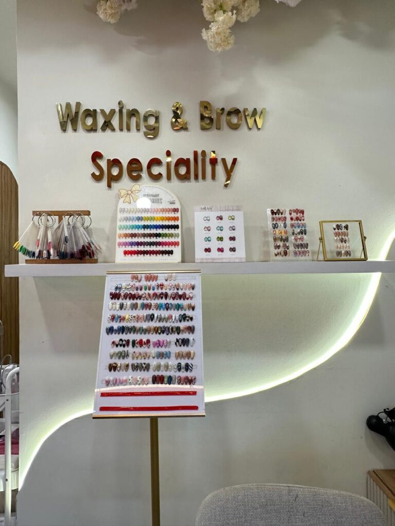 Dinding Waxing & Brow Speciality dengan contoh warna kuku di rak