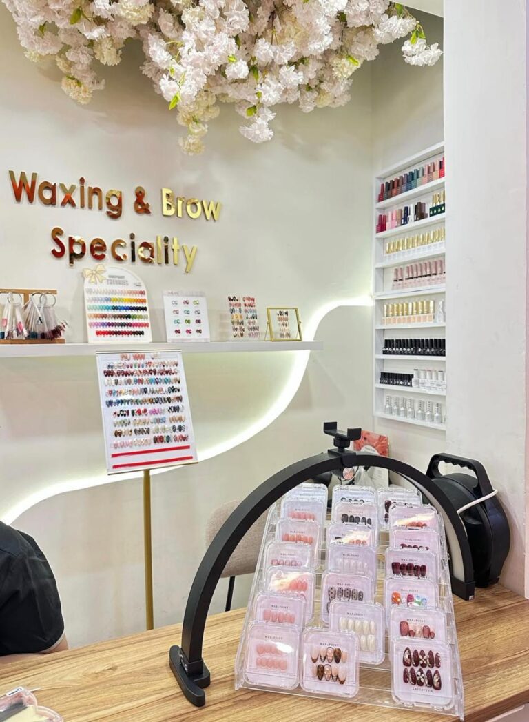 Meja nail art dengan lampu cincin, rak cat kuku, dan contoh kuku palsu